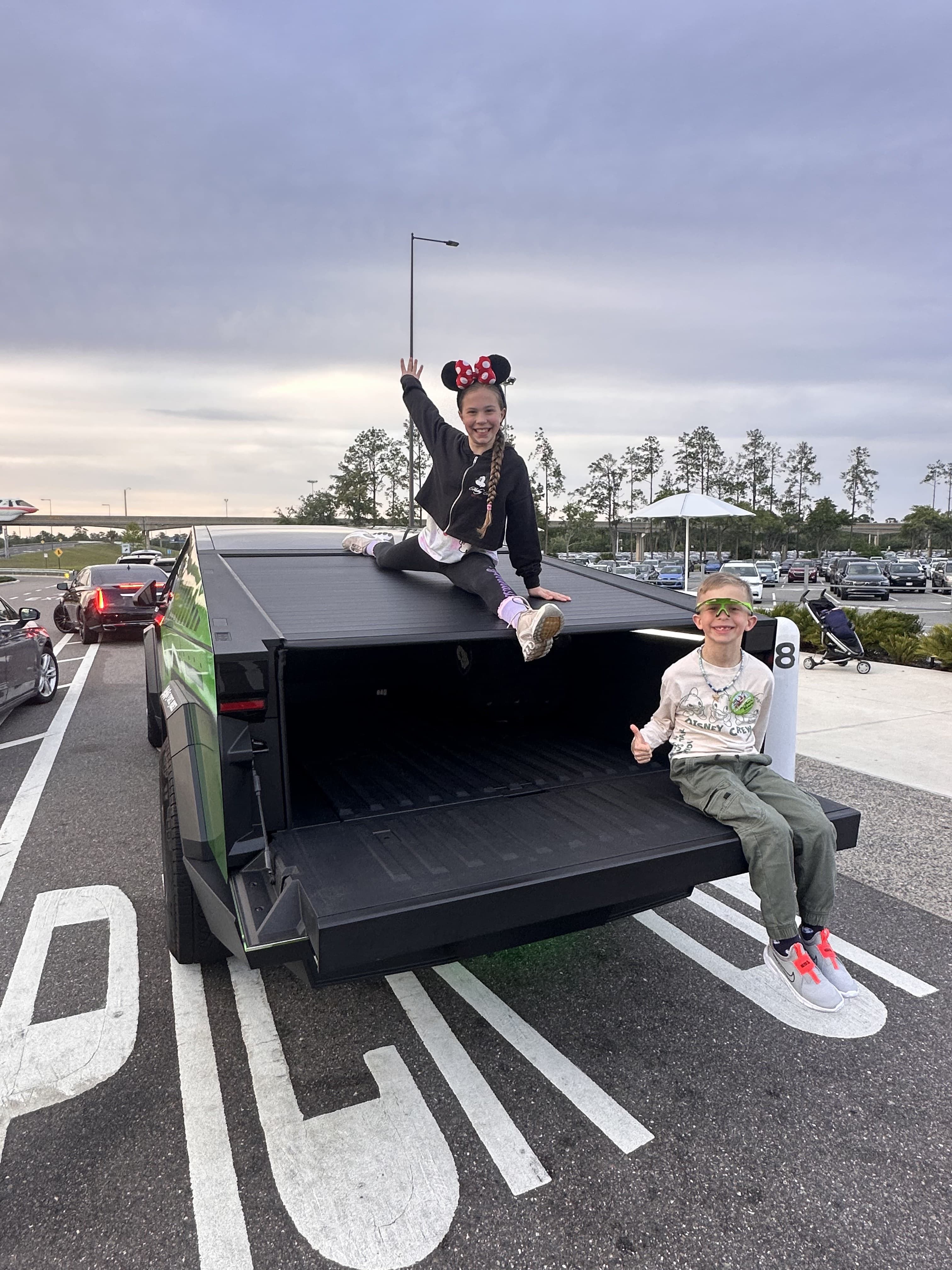 Kids sitting on the Cybertruck bed with Disney ears after a theme park mission